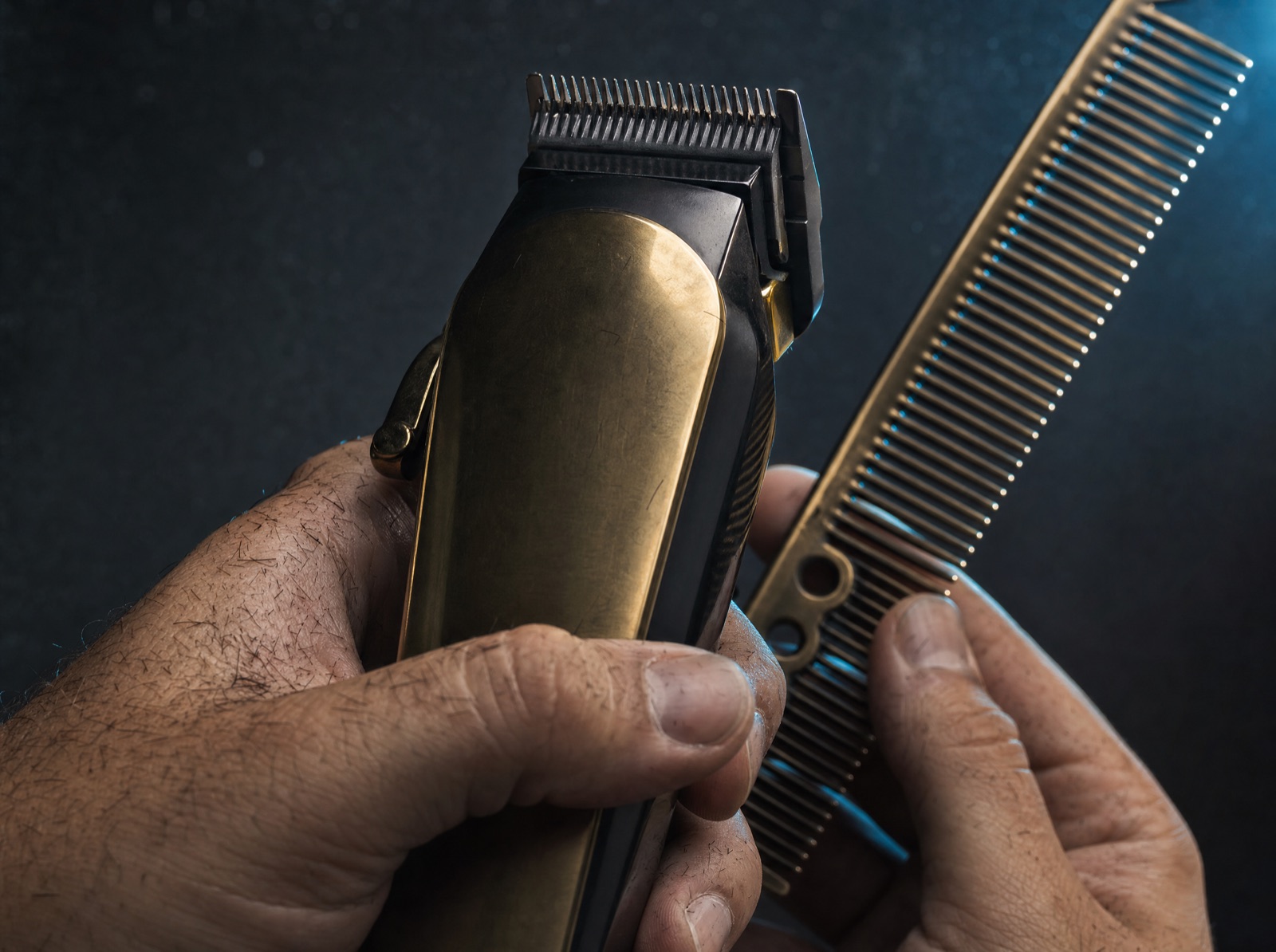 A precision close-up of a barber's hands working with clippers and a comb.